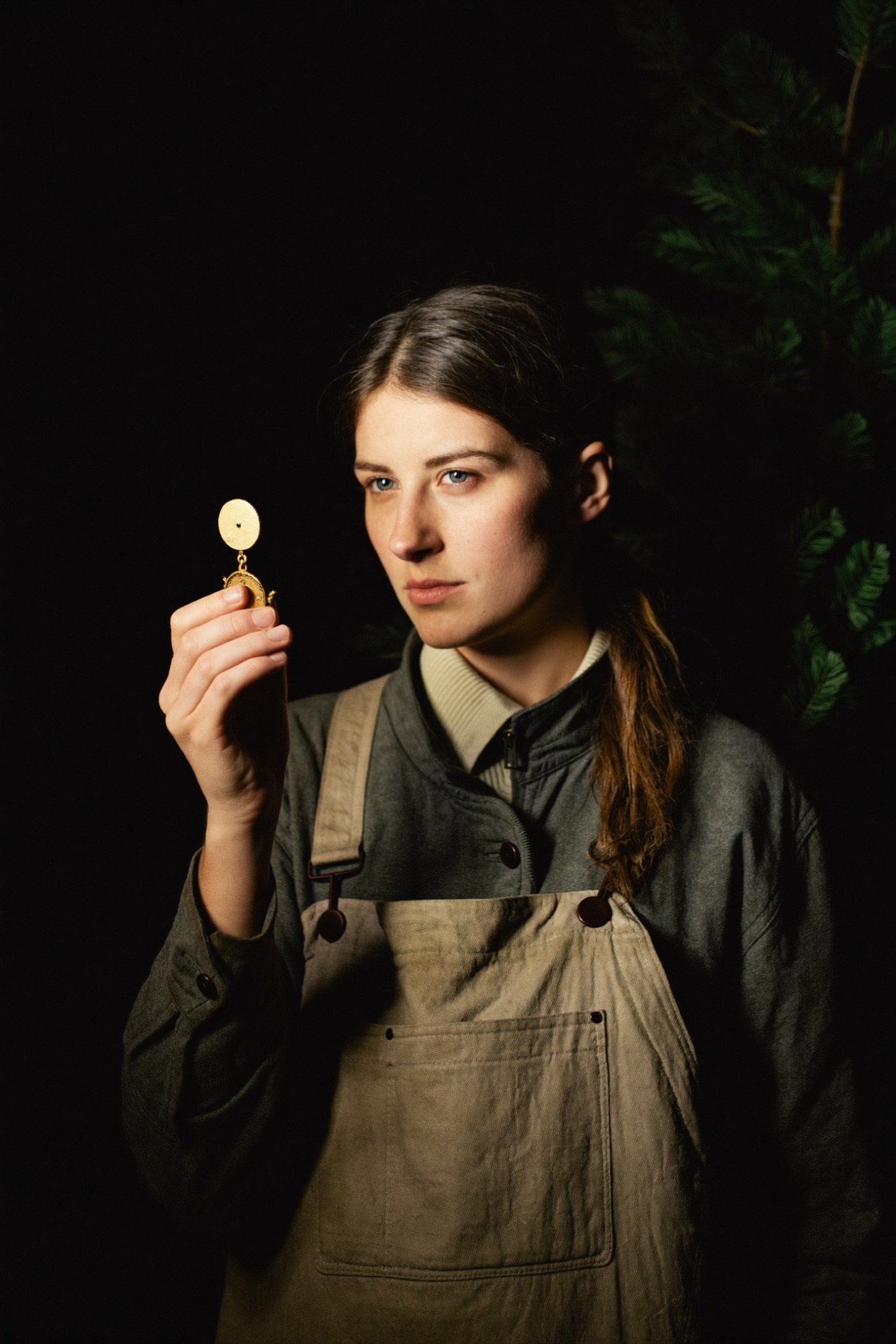Portrait of Marta Waldvogel, eighth-generation apprentice, examining a small brass movement by lantern light